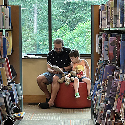 A father reading a book to his young son at the Library