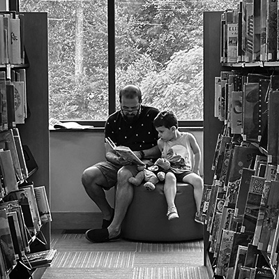 A father reading a book to his young son at the Library