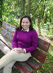 Closeup of Karin Lin-Greenberg sitting on a bench in the woods