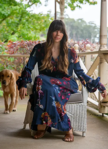 Close-up of Kate Morton sitting on a porch chair, with a dog next to her