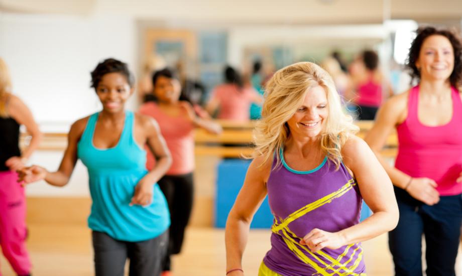 A group of smiling people dancing for fitness