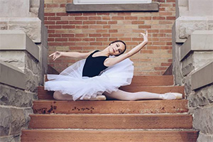 A woman wearing a tutu doing a ballet pose on stone steps