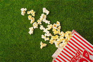 A bag of popcorn spilling out on to some artificial turf