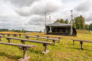 An outdoor theater with wooden benches set up in front a portable stage