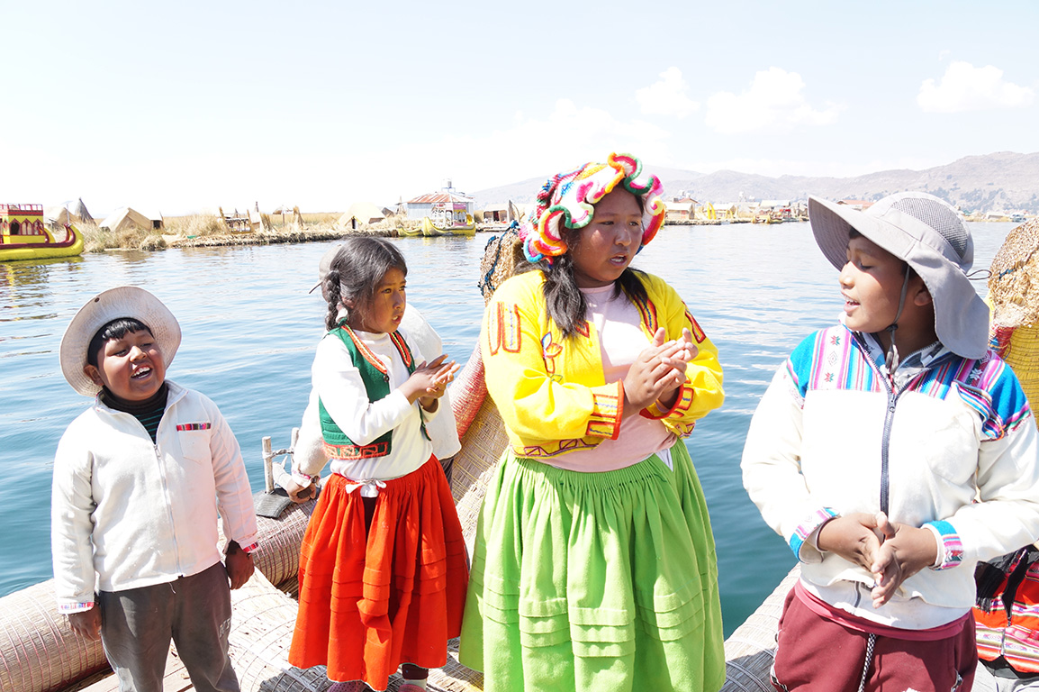 Four Peruvian kids singing on a dock by Lake Tititcaca