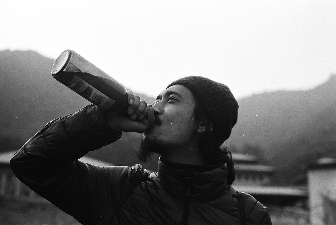 Black and white photo of a man drinking out of a wine bottle