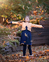 A child is throwing leaves in the air