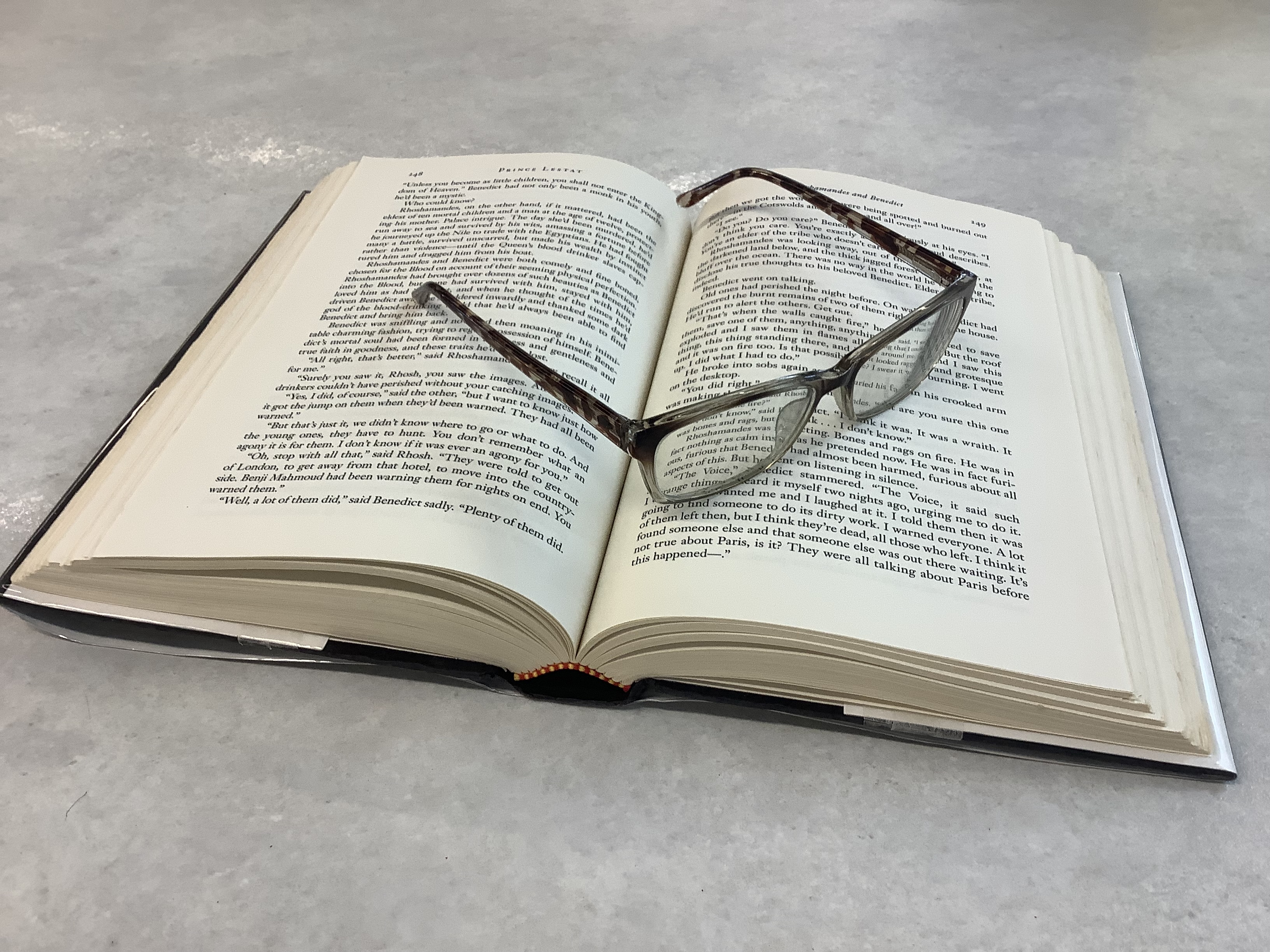 A book lying open with a pair of reading glasses on top
